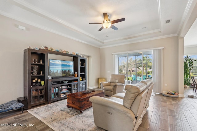 living room with a raised ceiling, wood finished floors, visible vents, and baseboards