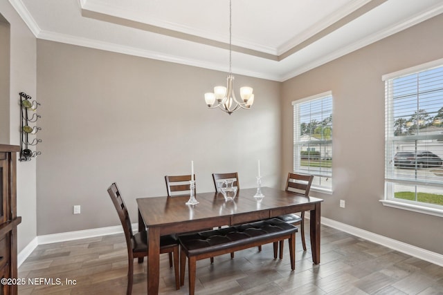 dining space featuring wood tiled floor, a tray ceiling, baseboards, and ornamental molding