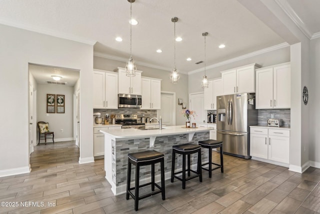 kitchen with visible vents, a breakfast bar area, stainless steel appliances, light countertops, and wood finish floors