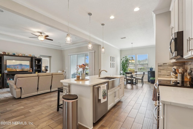 kitchen featuring stainless steel appliances, a sink, white cabinetry, wood tiled floor, and crown molding