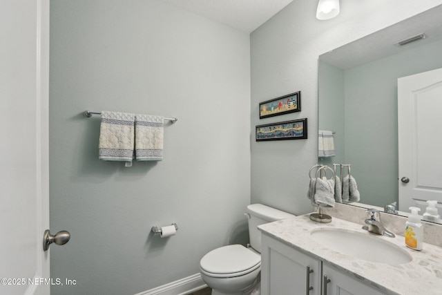 half bath featuring baseboards, visible vents, vanity, and toilet