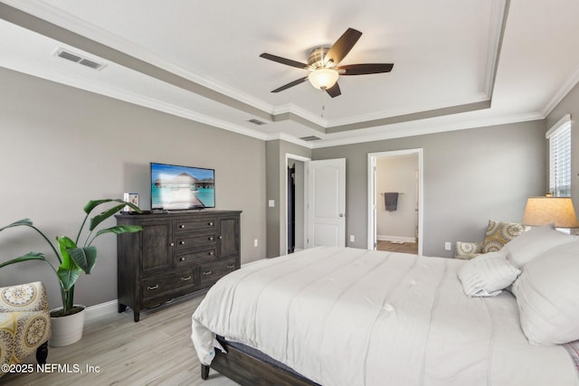 bedroom with a raised ceiling, visible vents, ornamental molding, light wood-type flooring, and baseboards