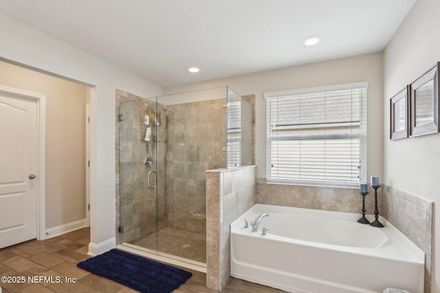 bathroom with recessed lighting, wood finished floors, baseboards, a shower stall, and a bath