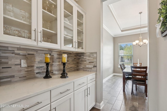 bar with a notable chandelier, baseboards, hanging light fixtures, tasteful backsplash, and crown molding