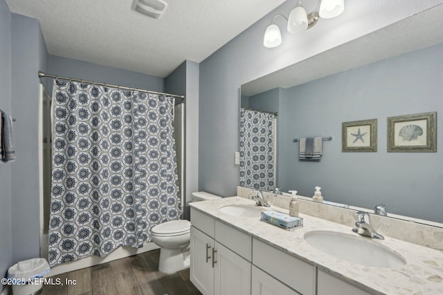 bathroom with toilet, visible vents, a sink, and wood finished floors