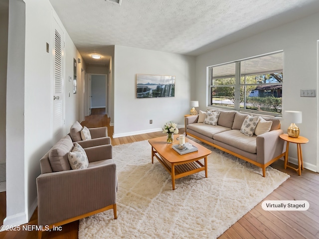 living area with light wood-style floors, baseboards, and a textured ceiling