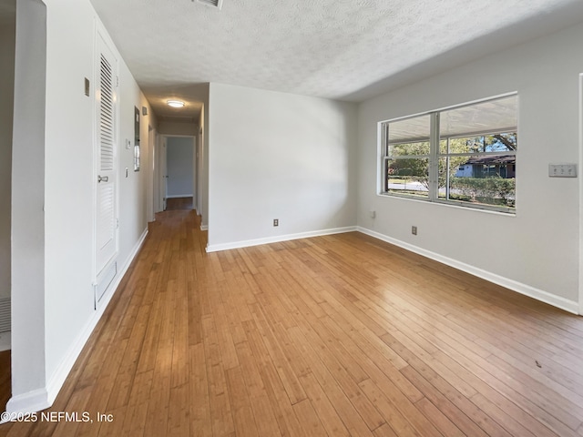 unfurnished room with light wood-type flooring and a textured ceiling