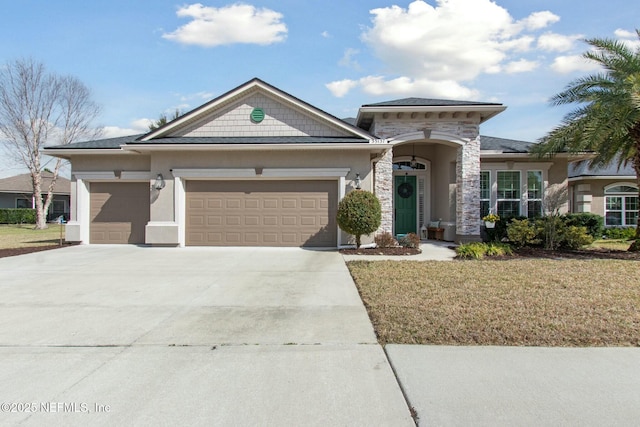 view of front of house featuring a garage, driveway, stone siding, and stucco siding