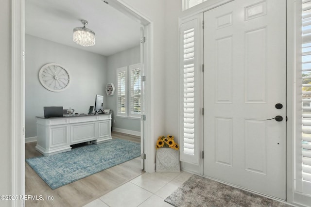 foyer featuring a notable chandelier, baseboards, and light tile patterned floors