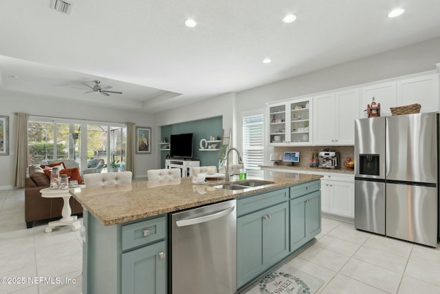 kitchen with stainless steel appliances, a sink, white cabinets, open floor plan, and an island with sink