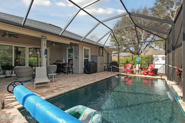 view of pool featuring a patio area, a fenced in pool, glass enclosure, and a ceiling fan