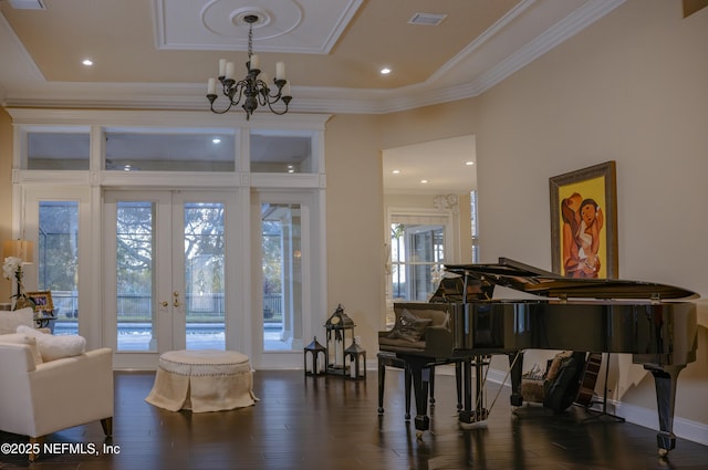 living area with baseboards, wood finished floors, an inviting chandelier, crown molding, and french doors