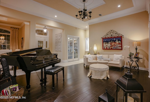 living room featuring visible vents, wood finished floors, a tray ceiling, french doors, and a notable chandelier