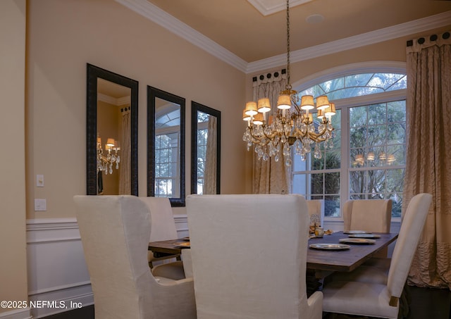 dining area with a chandelier, a wainscoted wall, and crown molding