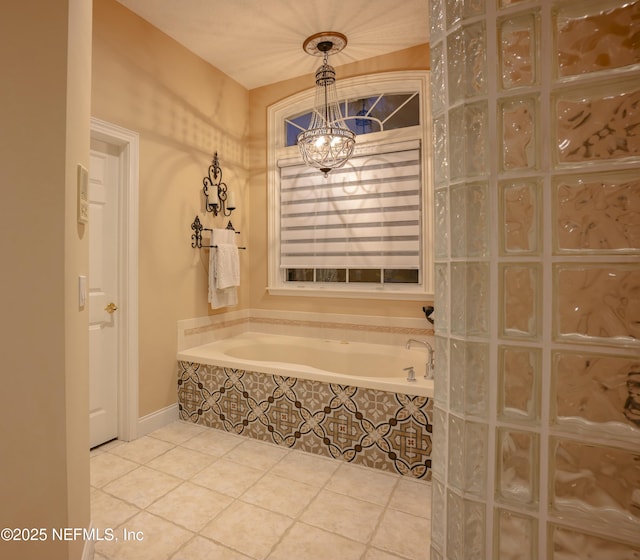 full bath with a garden tub, a notable chandelier, and tile patterned floors