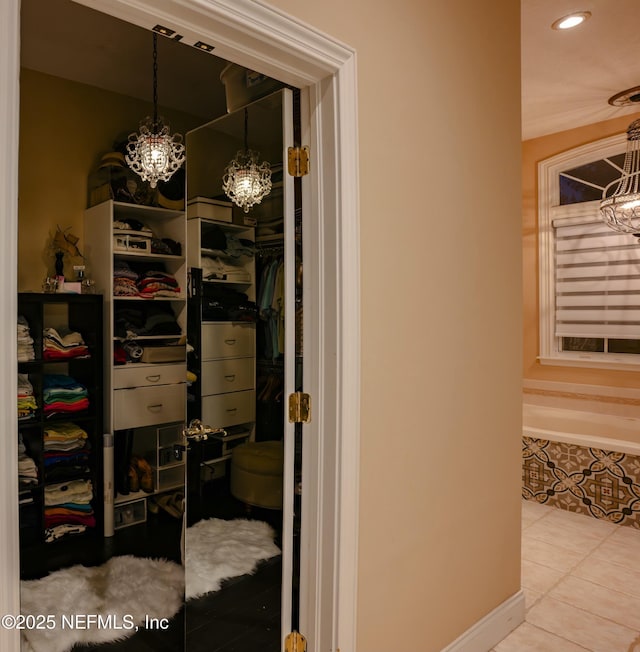 spacious closet with tile patterned flooring and an inviting chandelier