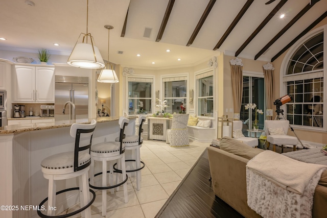 kitchen with lofted ceiling, light stone counters, open floor plan, hanging light fixtures, and stainless steel built in fridge