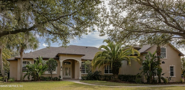 view of front of house featuring a shingled roof, a front yard, and stucco siding