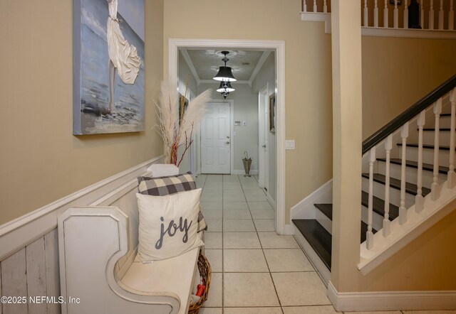 corridor with stairs, wainscoting, light tile patterned flooring, and crown molding