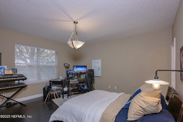 bedroom featuring a textured ceiling, baseboards, and wood finished floors