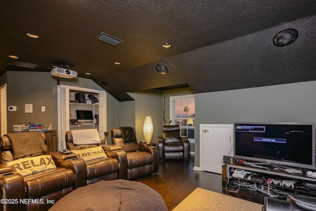 home theater room featuring lofted ceiling, visible vents, a textured ceiling, and wood finished floors