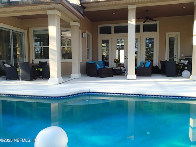 pool with french doors, a patio area, ceiling fan, and an outdoor living space