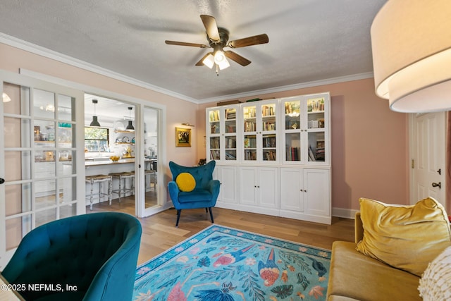 sitting room with a textured ceiling, ornamental molding, ceiling fan, and light hardwood / wood-style flooring