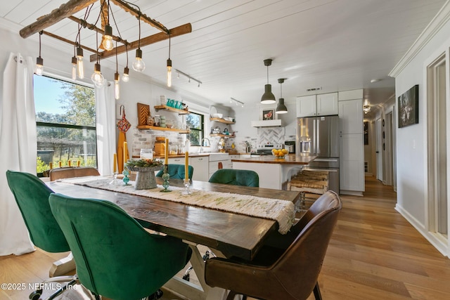 dining area with track lighting, sink, light hardwood / wood-style floors, and ornamental molding