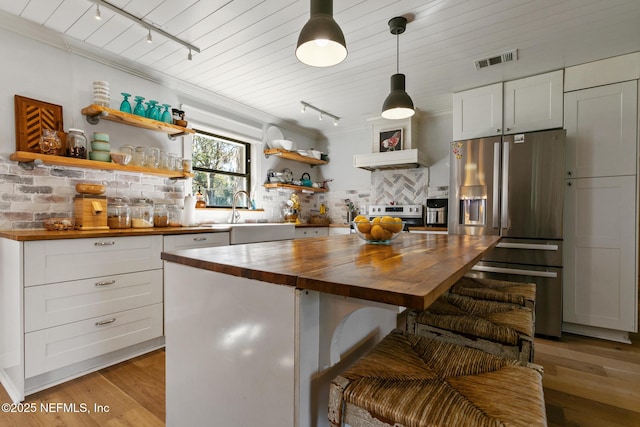 kitchen with wood counters, sink, a center island, white cabinetry, and stainless steel appliances