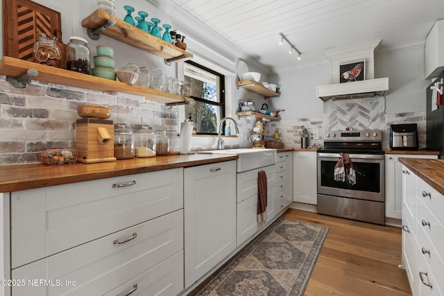 kitchen with electric stove, white cabinetry, butcher block counters, and sink