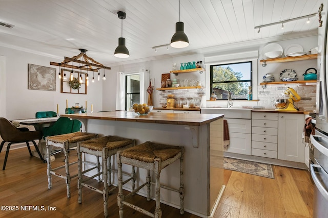 kitchen featuring white cabinets, light wood-type flooring, butcher block countertops, and ornamental molding