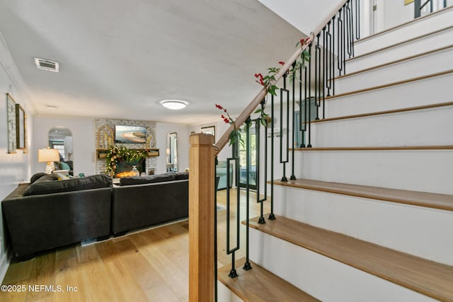 staircase featuring a fireplace and wood-type flooring