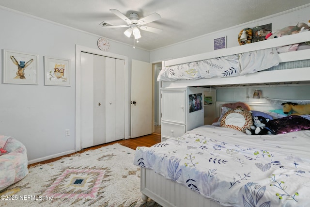 bedroom featuring ceiling fan, ornamental molding, a closet, and hardwood / wood-style floors