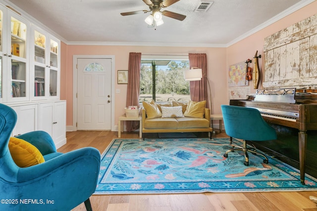 interior space featuring a textured ceiling, ornamental molding, ceiling fan, and light hardwood / wood-style flooring