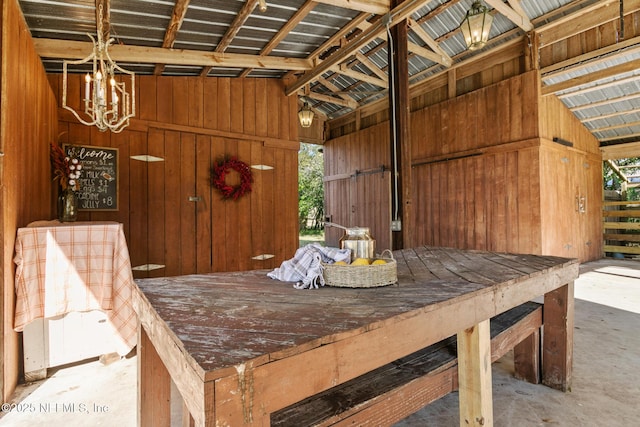 unfurnished dining area featuring lofted ceiling, concrete flooring, wooden walls, and an inviting chandelier