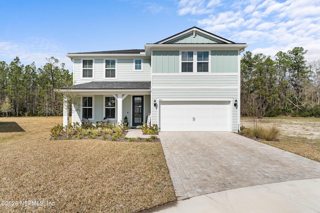 view of front facade with board and batten siding, a front yard, decorative driveway, and a garage