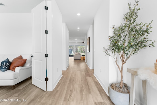 corridor featuring light wood-type flooring, baseboards, and recessed lighting