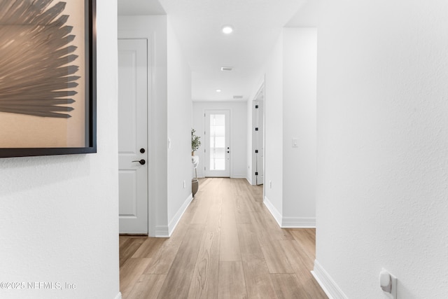 hall featuring light wood-style flooring and baseboards