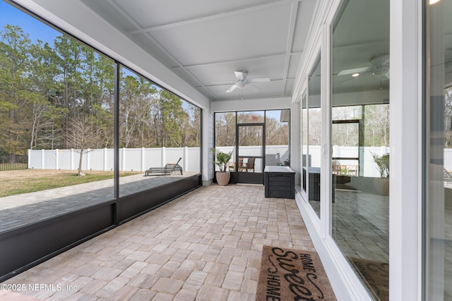 unfurnished sunroom featuring a ceiling fan and a wealth of natural light