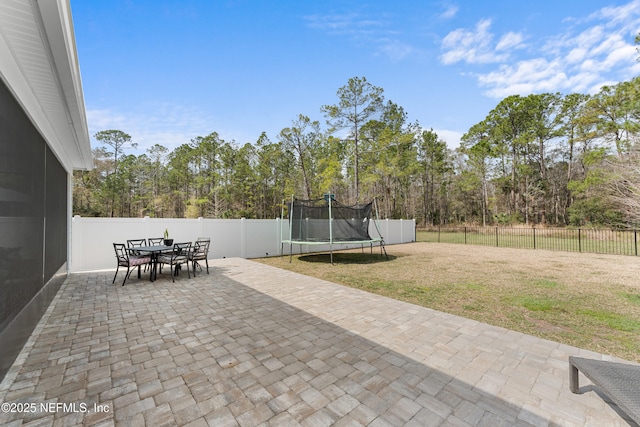 view of patio with a fenced backyard, a trampoline, and outdoor dining area