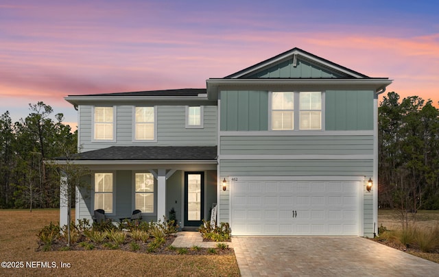 traditional-style house featuring board and batten siding, decorative driveway, covered porch, and an attached garage