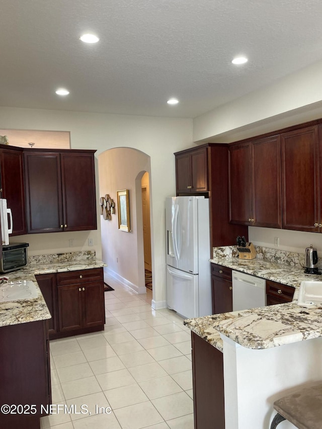 3383 Olympic Dr, Green Cove Springs, FL 32043 - kitchen featuring arched walkways, white appliances, light stone countertops, and baseboards