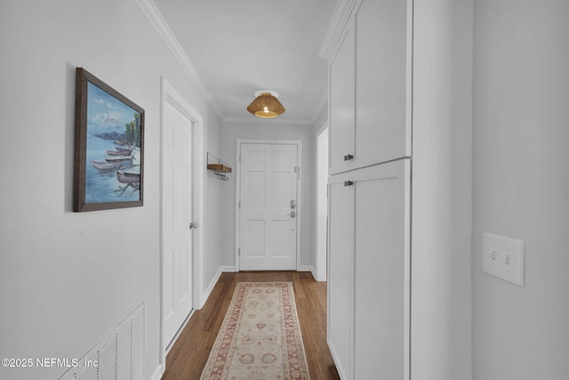 corridor with ornamental molding, visible vents, baseboards, and wood finished floors