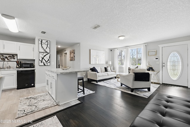 10605 Arnez Rd, Jacksonville, FL 32218 - living room featuring a textured ceiling, light wood-type flooring, visible vents, and baseboards
