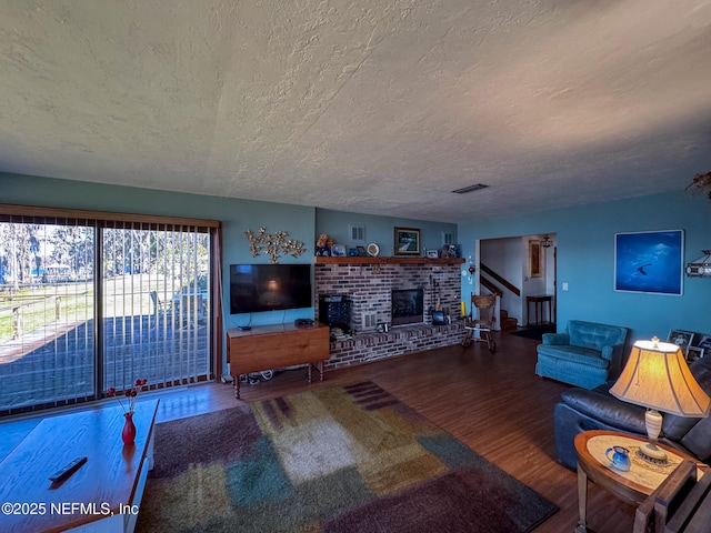 living room featuring stairs, a textured ceiling, wood finished floors, and visible vents