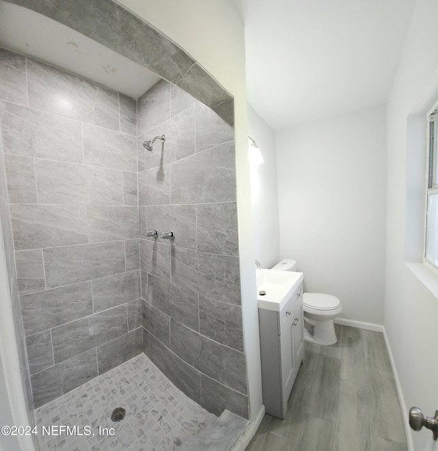 bathroom with vanity, a tile shower, toilet, and hardwood / wood-style floors