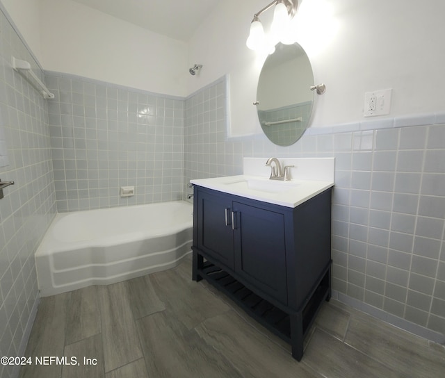 bathroom featuring hardwood / wood-style floors, shower / bathtub combination, tile walls, and vanity