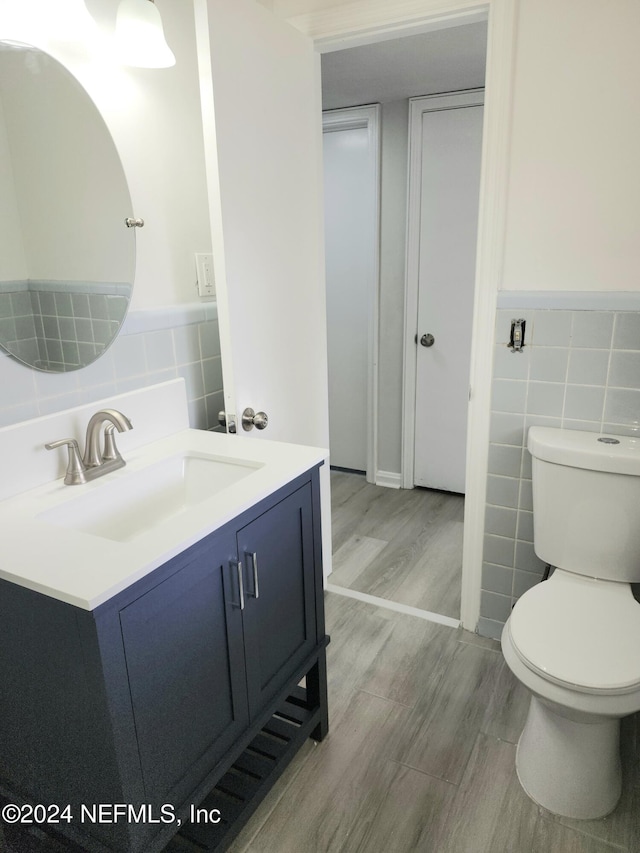 bathroom featuring hardwood / wood-style floors, toilet, tile walls, and vanity