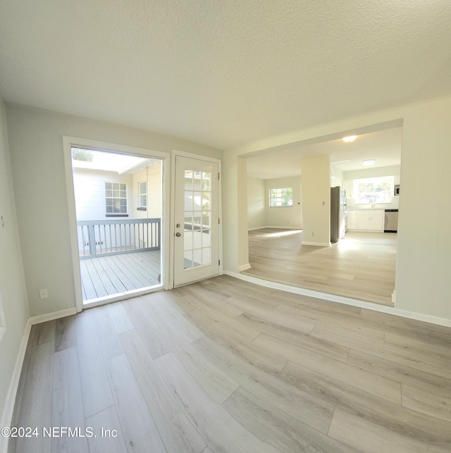 spare room with light wood-type flooring and a textured ceiling