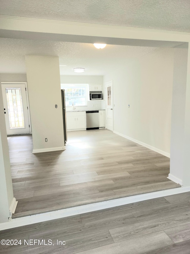 hall featuring sink, light wood-type flooring, and a textured ceiling